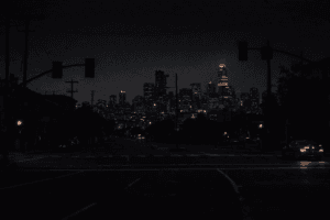 Dark San Francisco intersection during a citywide power outage, with unlit traffic signals and the downtown skyline dimly visible at night.