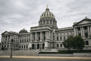 Pennsylvania State Capitol building in Harrisburg under an overcast sky, photographed in a neutral, documentary news style.